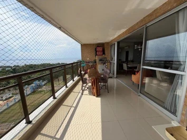 Varanda ampla com piso em cerâmica clara, mesa de madeira, proteção de tela e vista panorâmica.